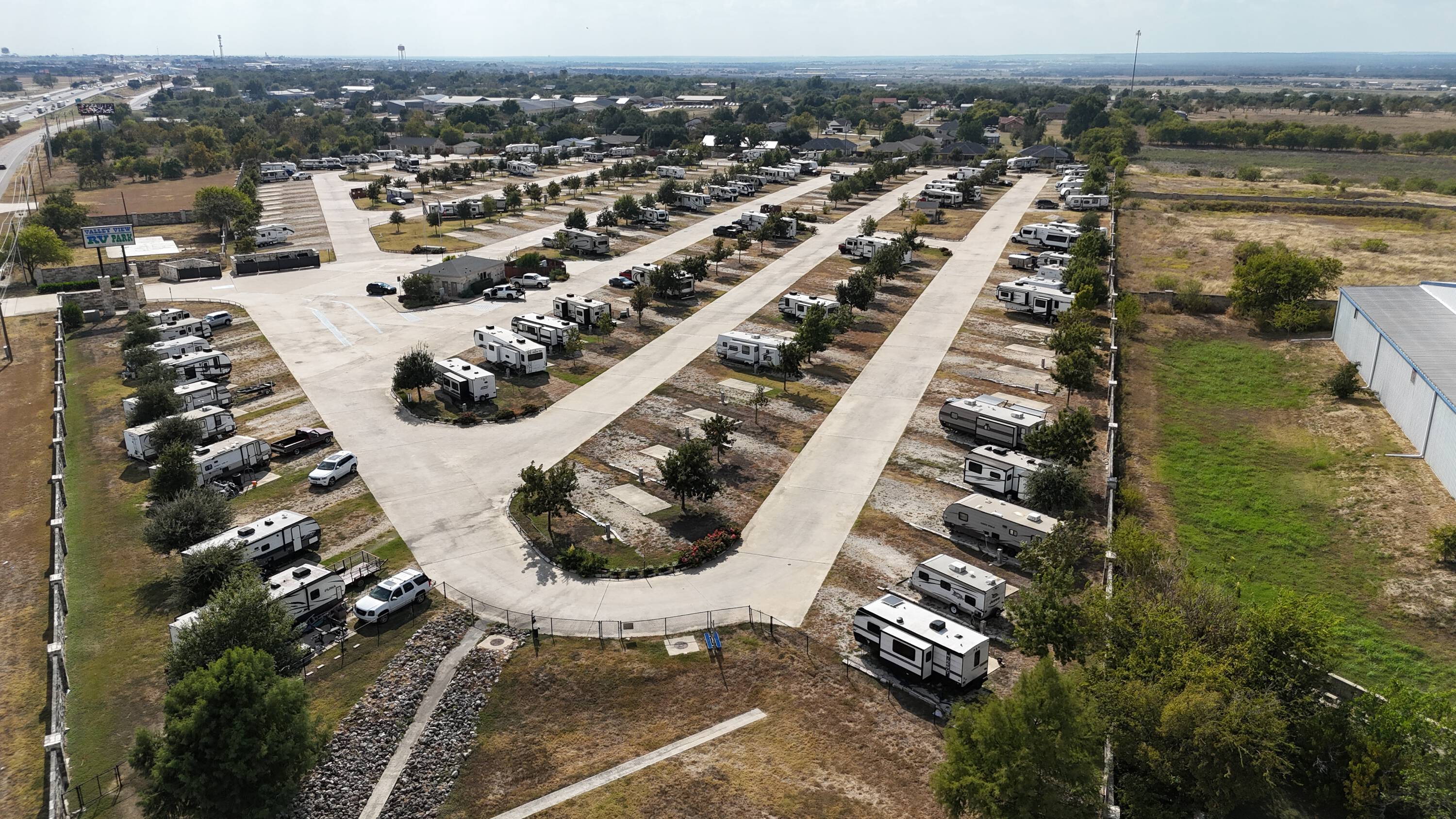 The same kind of machine running clean — orderly cream roads, occupied pads, stone entrance, quiet order. What “fixed” looks like when the park is working.